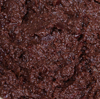 Close up of a dark brown olive paste